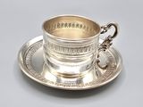 a silver cup and saucer on a silver plate