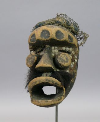 une image représentant un masque en bois posé sur un socle en métal
