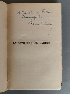 un livre ouvert, sur lequel figure un titre écrit à la main, posé sur une table