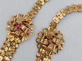 two pieces of gold jewelry are laying on a white surface