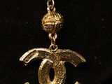 a gold necklace with a chain that has a chanel logo on it