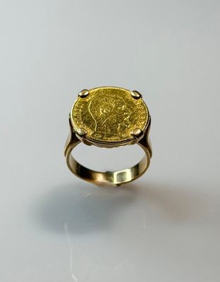 a close up of a gold ring with a coin on it