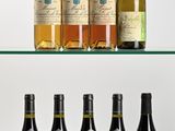 Plusieurs bouteilles de vin sont alignées sur une étagère en verre