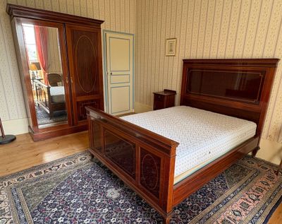 a bedroom with a bed, dresser, mirror, and rug
