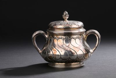 une théière ancienne en argent avec son couvercle, posée sur une table