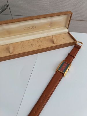 gucci watch in a box on a table with a leather strap
