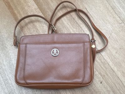 un sac à main marron posé sur un parquet, à côté d'un parquet