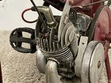 a small red motorcycle with a small engine on the ground