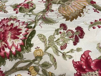 a close up of a bed with a red and green floral pattern on it