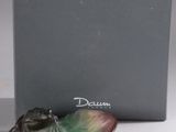 la figurine d'une grenouille est posée sur une feuille devant une boîte