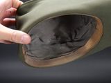 a person holding a green hat with a brown band