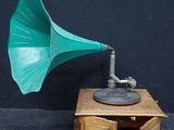un gramophone vert posé sur une table en bois près d'un mur noir