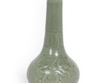 un vase vert posé sur une surface blanche
