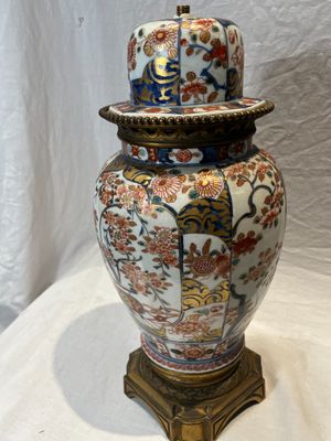 un vase posé sur une table, surmonté d'un chapeau