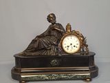 une statue de femme tenant une horloge sur une table