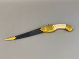 an old knife with a gold handle sitting on top of a table