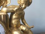 a gold statue of a baby sitting on a clock
