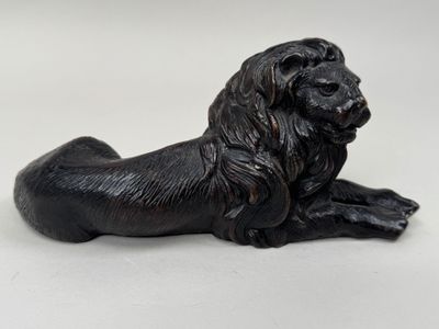 a black statue of a lion laying down on a white surface