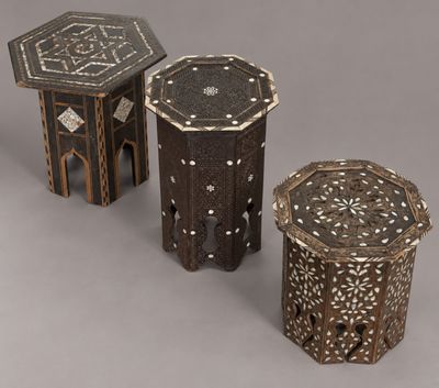 three small wooden tables with intricate designs on them on a gray background