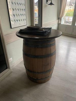 une table en forme de tonneau en bois, avec un plateau en verre, au milieu d'une pièce