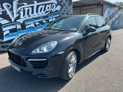 Une Porsche Cayenne noire est garée devant un mur couvert de graffitis