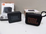 two black jbl mini speakers sitting on top of a table next to a box