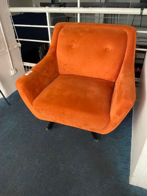 an orange chair sitting in front of a book shelf in a living room
