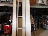 a pile of old doors in a warehouse with a shopping cart in the foreground
