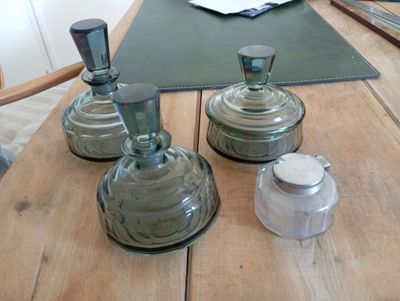 trois bocaux en verre posés sur une table en bois, accompagnés de salières et de poivrières