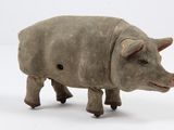 un petit jouet en bois représentant un cochon posé sur une surface blanche