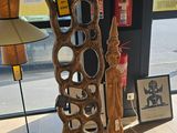 a tall wooden sculpture sitting on a table in front of a window
