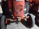 a man standing next to a red tractor in a garage
