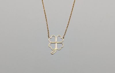 a gold necklace with a four leaf clover on it