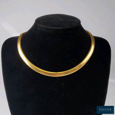 un gros plan d'un collier en or sur un mannequin