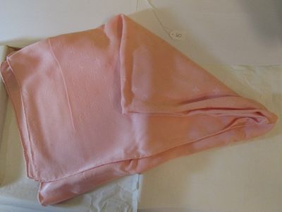 un tissu rose plié, posé dans une boîte sur une table