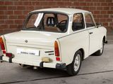 a small white car parked in front of a brick wall