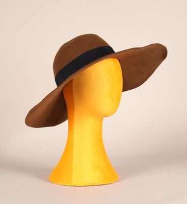 tête de mannequin jaune coiffée d'un chapeau marron orné d'un ruban noir