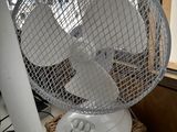 un ventilateur posé sur une table près d'une fenêtre