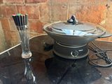 une mijoteuse posée sur une table, avec un couteau et une fourchette