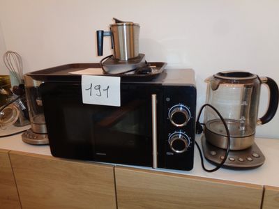 un micro-ondes noir posé sur un plan de travail, à côté d'une cafetière