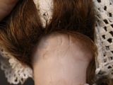 a close up of a doll ' s head with a lace hat on