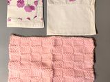 two pieces of pink and white knitted cloth with flowers on them