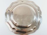 an antique silver plate with a circular edge on a white surface