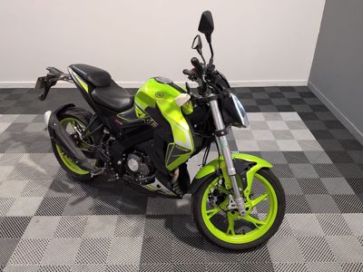 une moto de couleur citron vert et noire garée sur un sol à damier