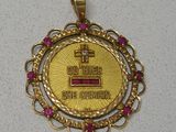 a gold medal with a cross on it on a white surface