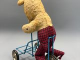 un ours en peluche qui fait du vélo sur un petit vélo jouet