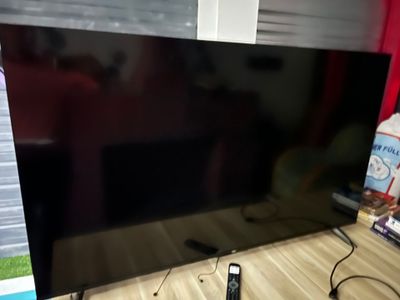 une télévision à écran plat posée sur un bureau, avec une télécommande