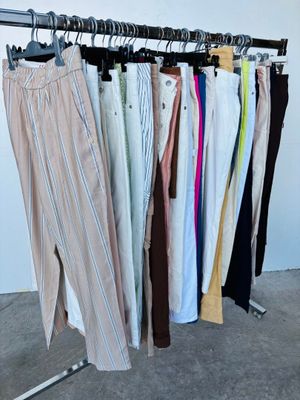 de nombreux pantalons suspendus à un portant devant un mur blanc