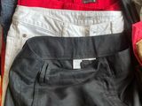 several pairs of men ' s pants sitting on top of a bed