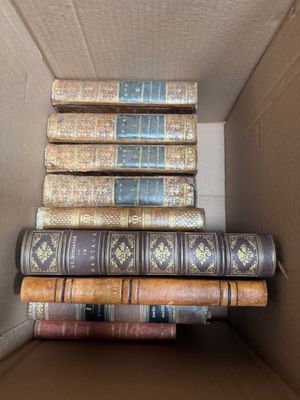 several books are stacked in a cardboard box on top of each other